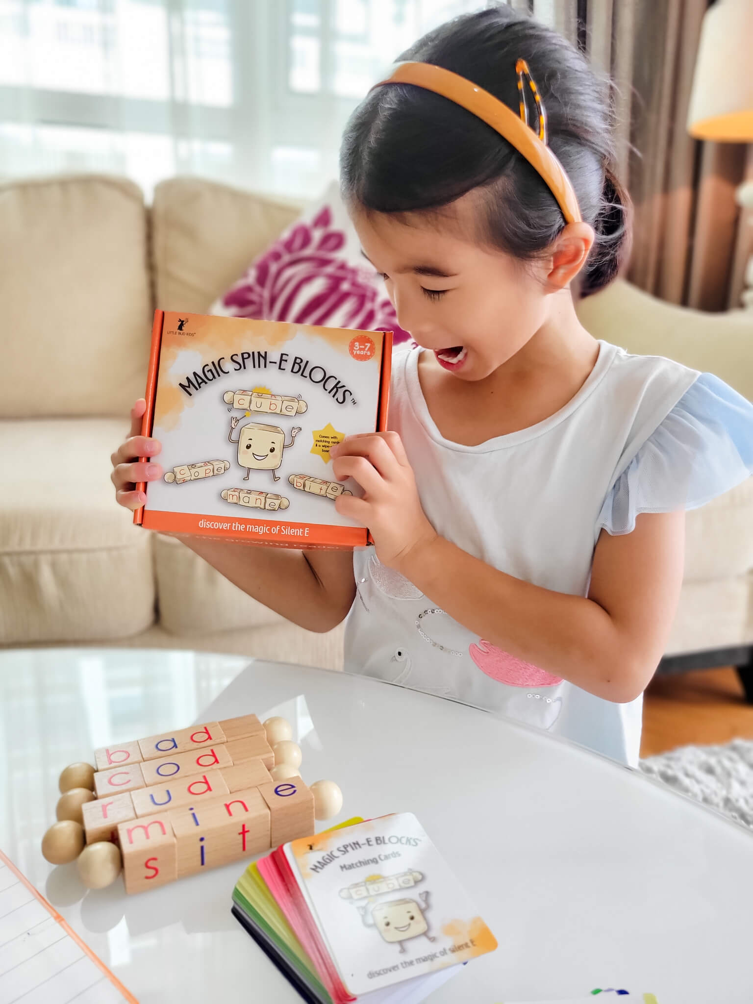 Child playing with Magic Spin-E Blocks phonics toy set, featuring wooden word-building blocks and flashcards for teaching silent E, long vowels, and CVC to CVCe word transformation in early literacy.