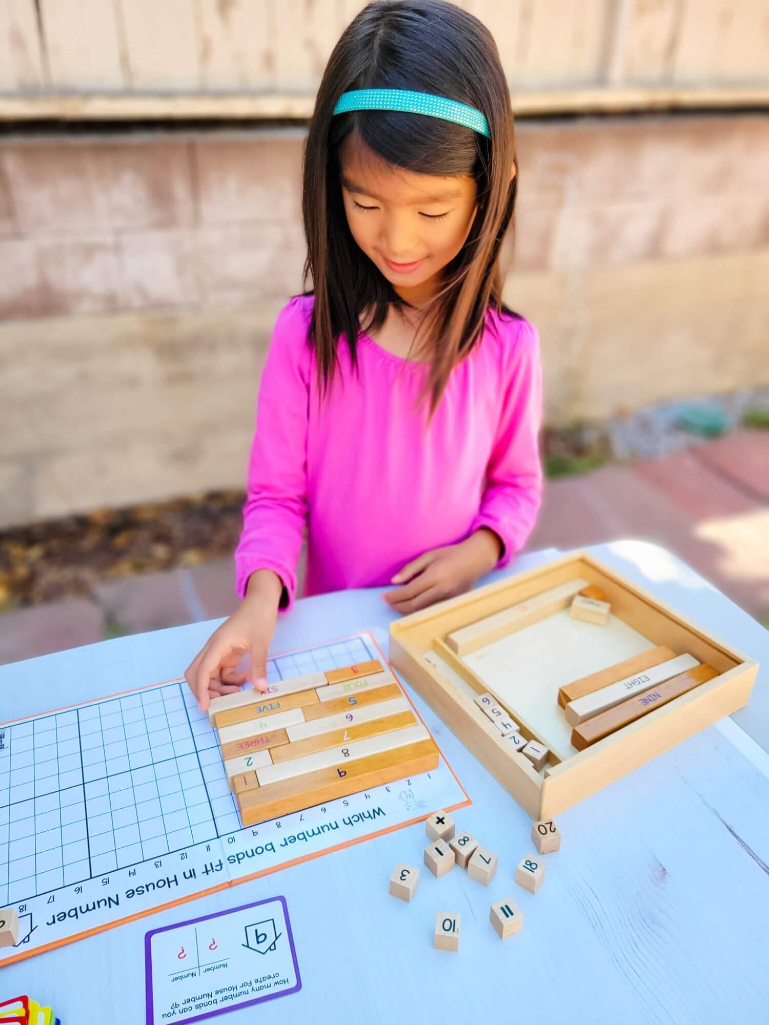 Girl playing with Montessori number rods from Little Bud Kids, a Number Bonds Math Game to learn Number Facts Families