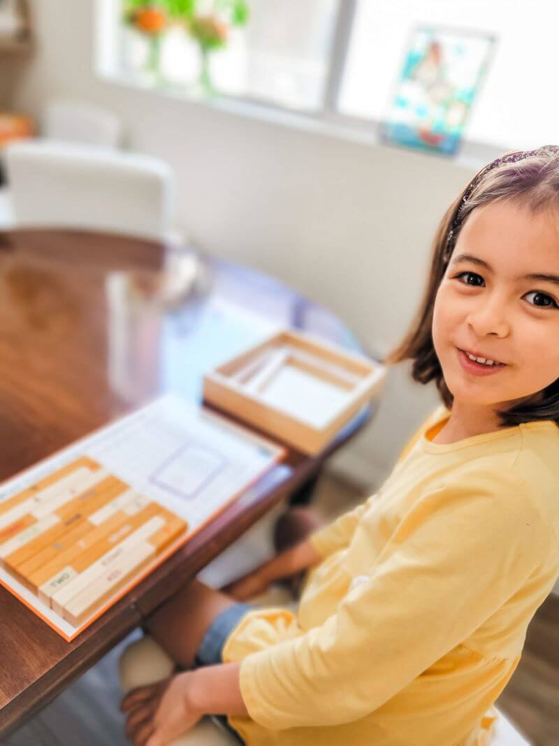 Girl playing with Singapore Math Number Rods, Cuisenaire Rods to learn addition and number bonds
