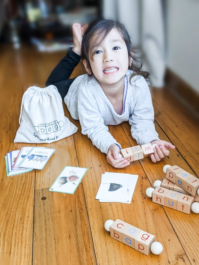 Girl learning to read using phonetic reading blocks by Little Bud Kids