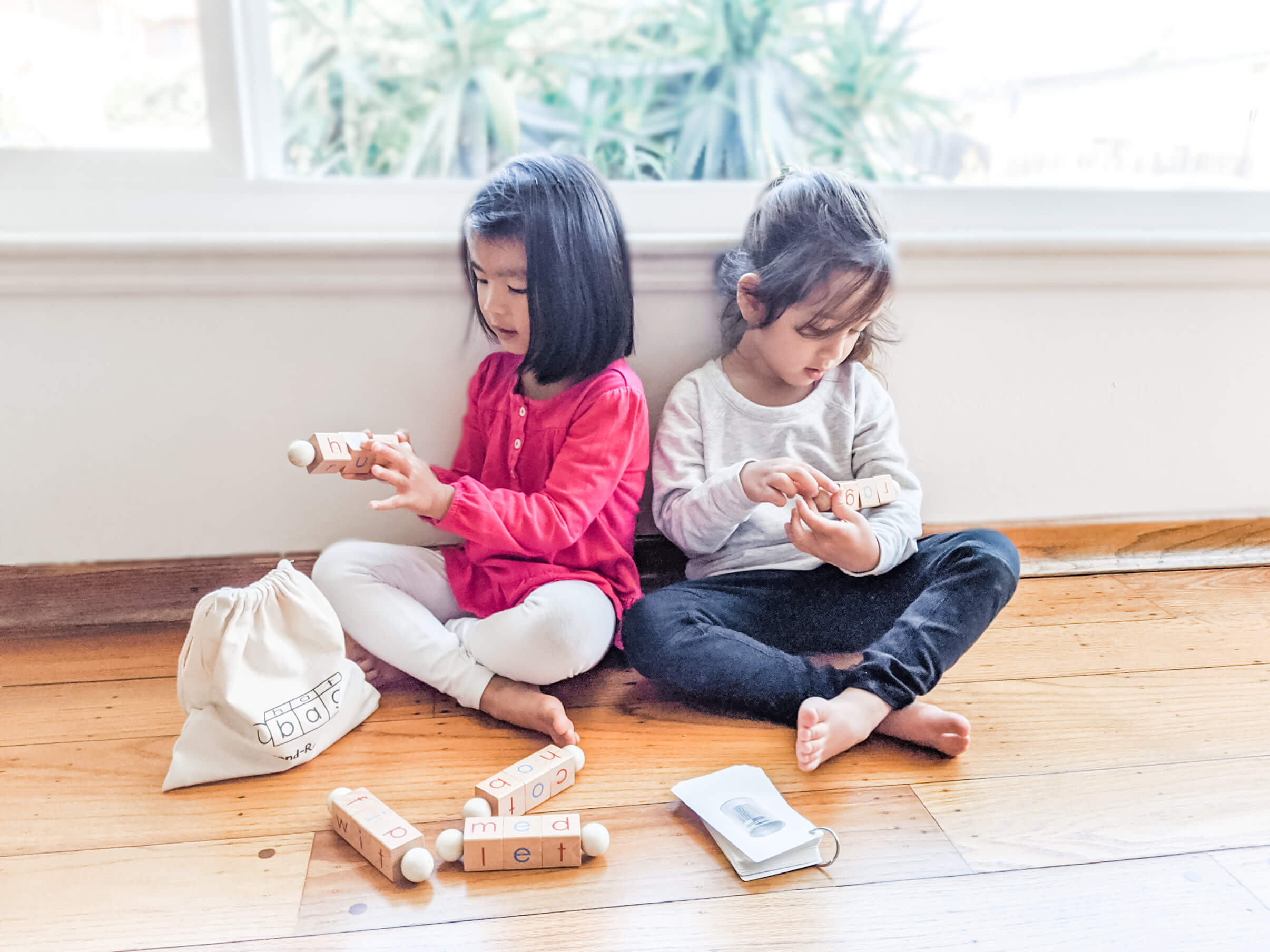 Girls learning reading using a phonics toy by Little Bud Kids