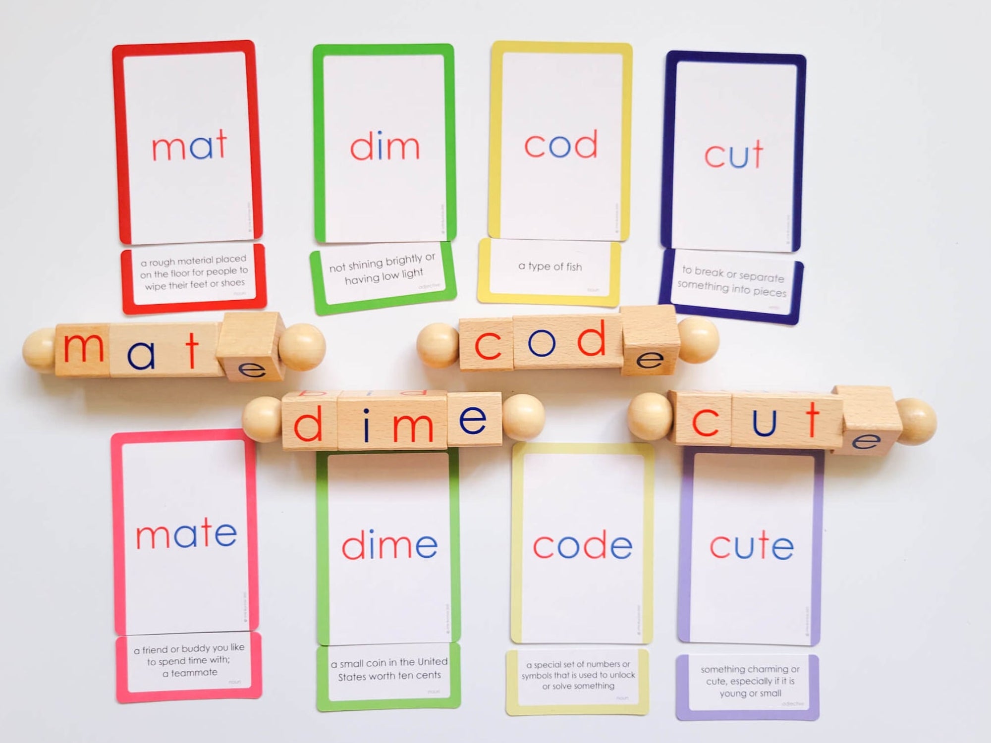 CVCE word definition cards and rotating wooden blocks for teaching silent E transformations includes words like mat, dim, cod, cut, and their CVCE forms mate, dime, code, and cute